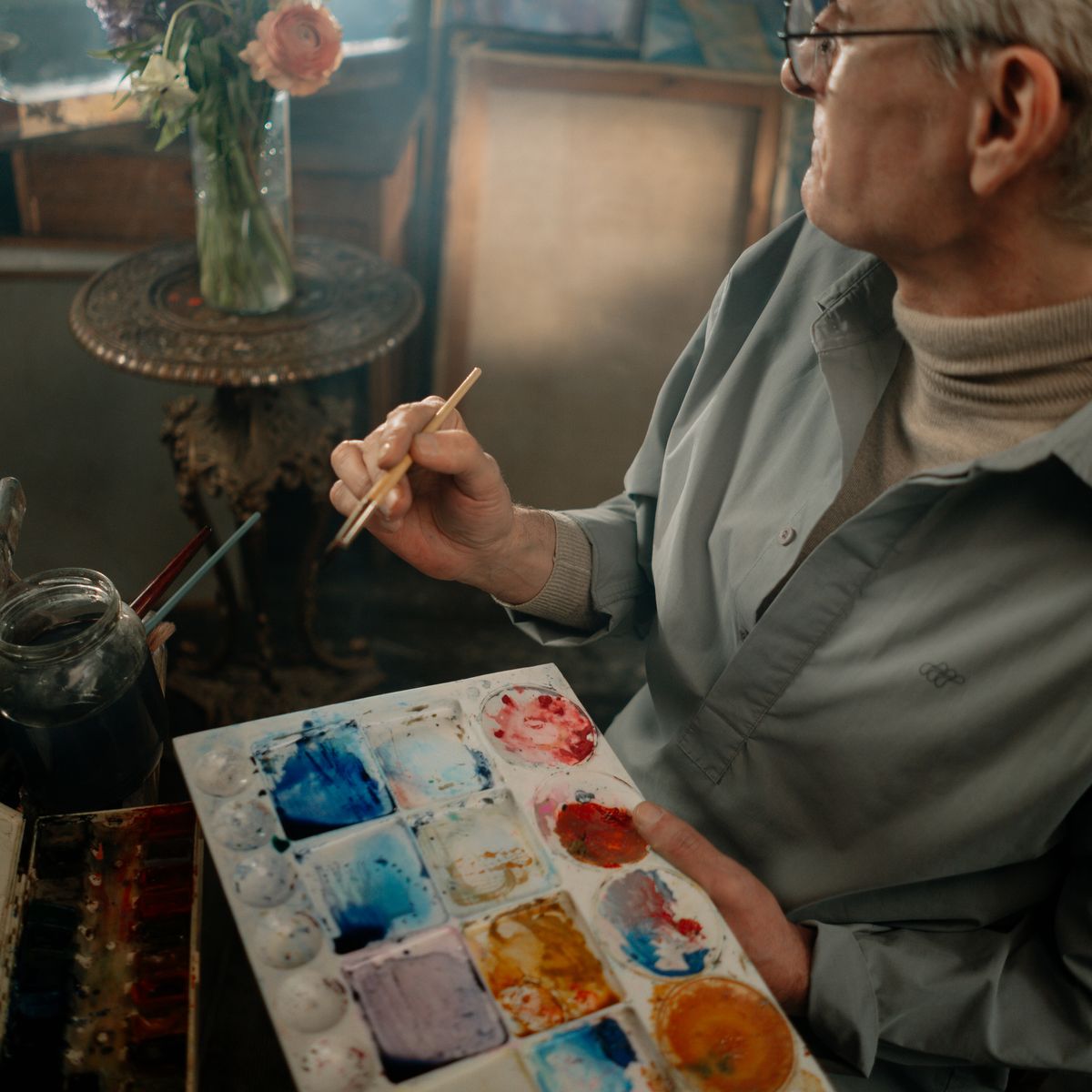 An older adult mixing colors on a paint palette during a calm art activity